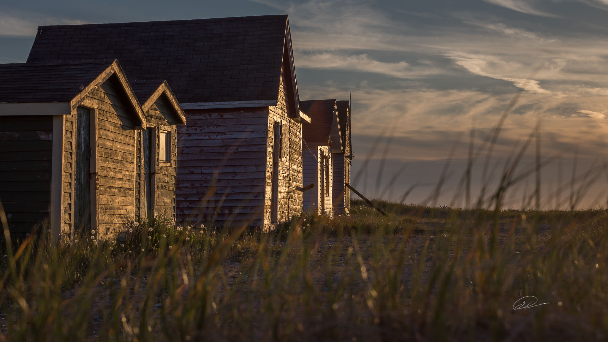Weathered fishing cabins at Old House Rocks at golden hour